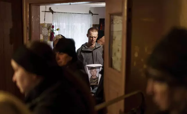 A man holds a photograph of Dmytro Shapovalov, a Ukrainian serviceman, during his funeral ceremony in Yosypivka village, Vinnytsia region, Ukraine, on Friday, June 13, 2025. (AP Photo/Evgeniy Maloletka)