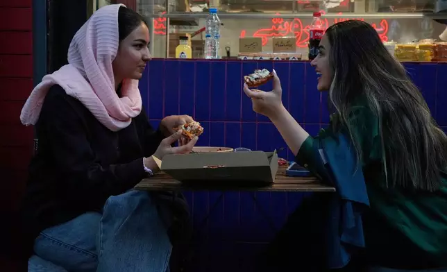 Women eat pizza in the outdoor area of a restaurant in northern Tehran, Iran, Monday, June 2, 2025. (AP Photo/Vahid Salemi)