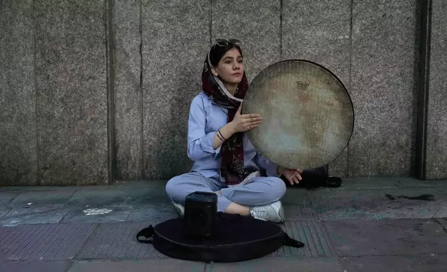 A street musician plays the Daf, a hand-held Persian drum, on a sidewalk in northern Tehran, Iran, Monday, June 2, 2025. (AP Photo/Vahid Salemi)