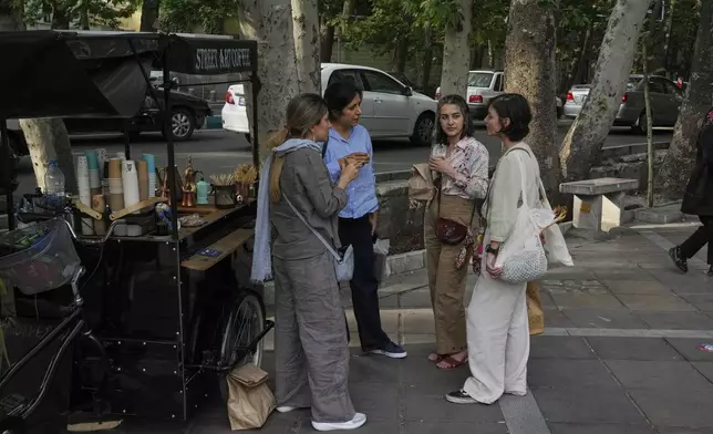 Iranian women drink coffee on the sidewalk in northern Tehran, Iran, Saturday, May 3, 2025. (AP Photo/Vahid Salemi)