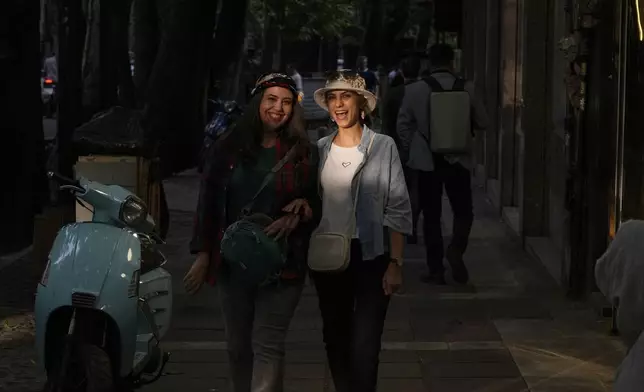 Two women share a laugh as they walk on the sidewalk in northern Tehran, Iran, Saturday, May 3, 2025. (AP Photo/Vahid Salemi)