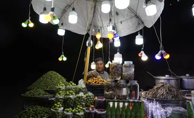 A vendor adjusts fruits on his stand on the roadside of eastern entrance of Tehran, Iran, Thursday, May 15, 2025. (AP Photo/Vahid Salemi)