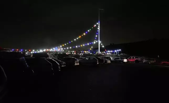 Decorative lights glow beside cars parked along the roadside at the eastern entrance of Tehran, as people enjoy the evening in Iran, Thursday, May 15, 2025. (AP Photo/Vahid Salemi)
