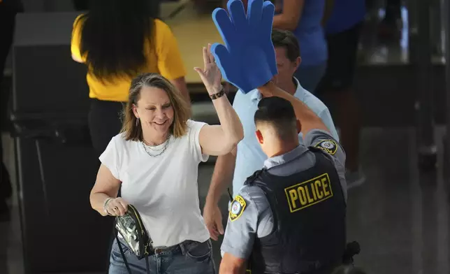 A fan high-fives a police officer at a security checkpoint before Game 7 of the NBA Finals basketball series between the Indiana Pacers and the Oklahoma City Thunder Sunday, June 22, 2025, in Oklahoma City. (AP Photo/Julio Cortez)
