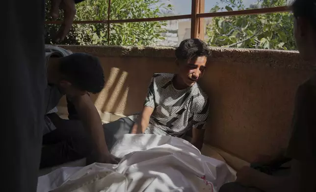 Palestinians mourn beside the body of Abdul Rahman Al-Qudra who was killed while heading to a Gaza aid hub, during his funeral at the Nasser Hospital in Khan Younis, southern Gaza Strip, Tuesday, June 3, 2025. (AP Photo/Abdel Kareem Hana)