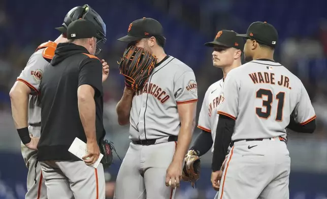 San Francisco Giants starting pitcher Robbie Ray, center, talks on the mound during the second inning of a baseball game against the Miami Marlins, Saturday, May 31, 2025, in Miami. (AP Photo/Lynne Sladky)