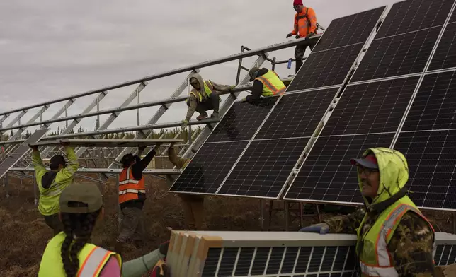 Workers install panels at a solar project Wednesday, May 21, 2025, in Galena, Alaska. (AP Photo/John Locher)