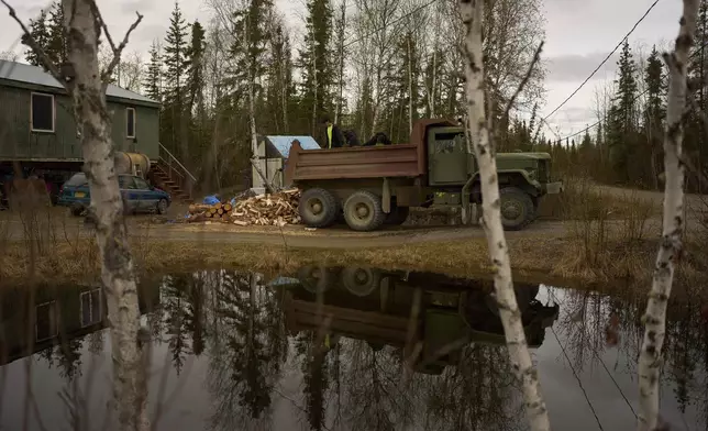 Nathan Moses, from left, Morris Demoski and Marissa McCarty deliver wood to an elder Monday, May 19, 2025, in Galena, Alaska. (AP Photo/John Locher)