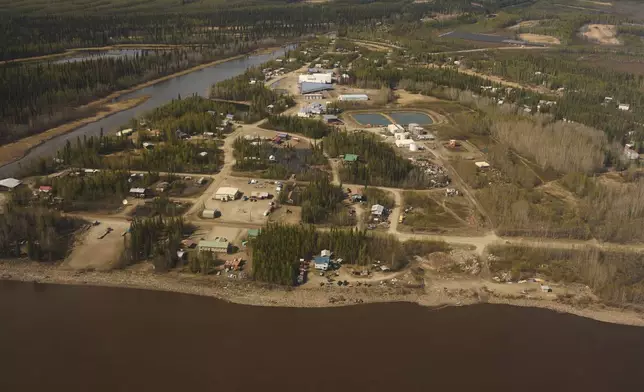 Buildings line dirt roads near the Yukon River, front, Friday, May 23, 2025, in Galena, Alaska. (AP Photo/John Locher)