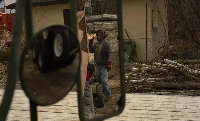 Morris Demoski tosses a split log into the back of a dump truck Thursday, May 22, 2025, in Galena, Alaska. (AP Photo/John Locher)