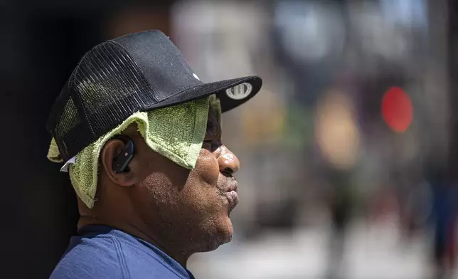Dwayne Chapaman wears a wet cloth on his head to combat the heat while crossing Broad Street in Philadelphia. Wednesday, June 25, 2025. (Jose F. Moreno/The Philadelphia Inquirer via AP)