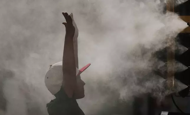 A boy cools off in a mister at Kauffman Stadium before a baseball game between the Kansas City Royals and the Tampa Bay Rays, Wednesday, June 25, 2025, in Kansas City, Mo. (AP Photo/Charlie Riedel)