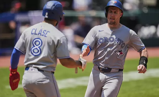 Toronto Blue Jays' Tyler Heineman, right, is greeted by Jonatan Clase (8) after scoring in the third inning of a baseball game against the Cleveland Guardians in Cleveland, Thursday, June 26, 2025. (AP Photo/Sue Ogrocki)