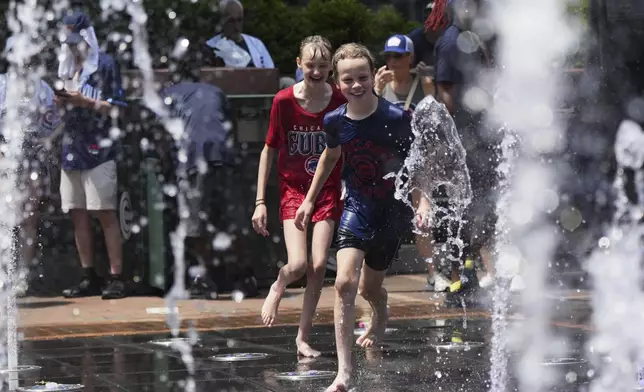 Jude Puroway, right, and Bay Puro cool off at a fountain during hot weather in Chicago, Sunday, June 22, 2025. (AP Photo/Nam Y. Huh)
