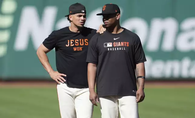San Francisco Giants' Willy Adames, left, and Rafael Devers stand on the field while warming up before a baseball game against the Boston Red Sox in San Francisco, Friday, June 20, 2025. (AP Photo/Jeff Chiu)