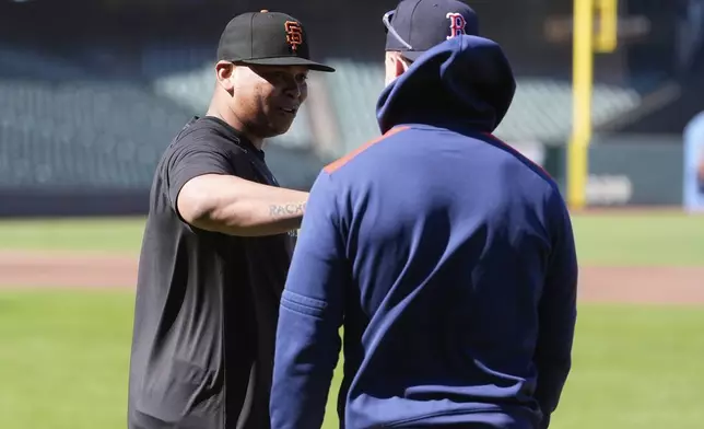 San Francisco Giants' Rafael Devers, left, talks with Boston Red Sox's Romy Gonzalez before a baseball game in San Francisco, Friday, June 20, 2025. (AP Photo/Jeff Chiu)