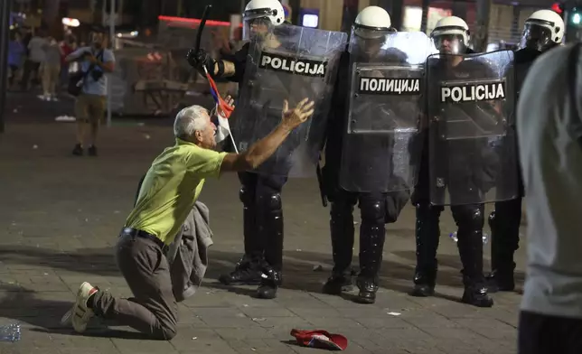 An elderly man kneels in front of police line at the end of a rally pressing for an early election after nearly eight months of almost daily anti-corruption demonstrations that have shaken the populist government of President Aleksandar Vucic, in Belgrade, Serbia, Saturday, June 28, 2025. (AP Photo/Marko Drobnjakovic)