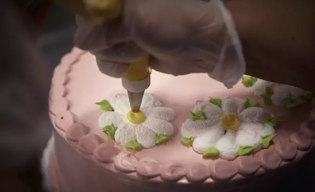 An employee decorates a cake inside Walmart Supercenter on Wednesday, May 28, 2025, in North Bergen, N.J. (AP Photo/Andres Kudacki)