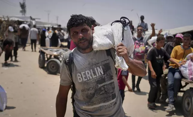 Omar al-Hobi, 43, from Rafah, carries a bag of food he collected at a distribution center run by private contractor the Gaza Humanitarian Foundation in the southern Gaza Strip, as he arrives at his tent in Khan Younis, Tuesday, June 10, 2025. (AP Photo/Abdel Kareem Hana)