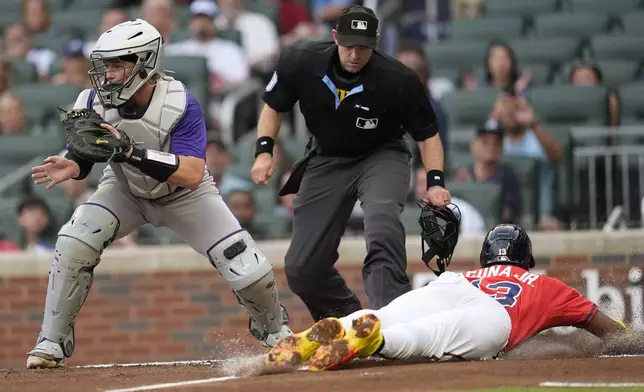 Atlanta Braves Ronald Acuña Jr. (13) slides to home plate against Colorado Rockies catcher Hunter Goodman (15) in the first inning of a baseball game, Friday, June 13, 2025, in Atlanta. (AP Photo/Mike Stewart)