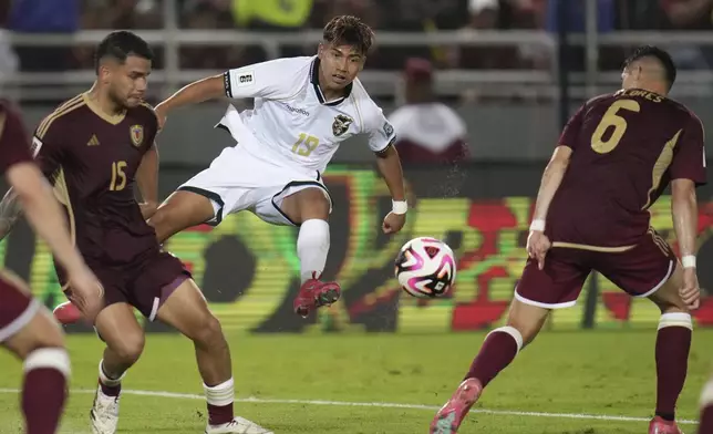 Bolivia's Jhon Velasquez, center, kicks the ball during a World Cup 2026 qualifying soccer match against Venezuela in Maturin, Venezuela, Friday, June 6, 2025. (AP Photo/Ariana Cubillos)