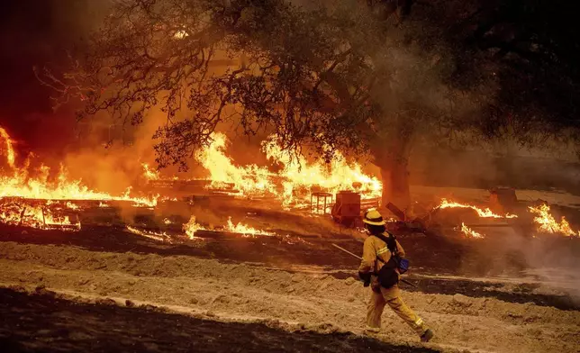 FILE - A firefighter passes flames while battling the Glass Fire in a Calistoga, Calif., vineyard Oct. 1, 2020. (AP Photo/Noah Berger, File)