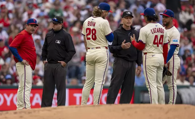 Philadelphia Phillies manager Rob Thomson, left, umpire Derek Thomas, second from left, on the balk call against starting pitcher Jesus Luzardo, second from right, who is talking with umpire Dan Iassogna, third from left, during the fourth inning of a baseball game against the Milwaukee Brewers, Saturday, May 31, 2025, in Philadelphia. (AP Photo/Chris Szagola)