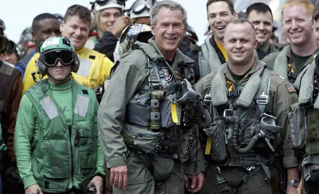 FILE - President George W. Bush poses with sailors and pilots aboard the USS Abraham Lincoln off the California coast after landing in a small jet May 1, 2003. (AP Photo/J. Scott Applewhite, File)
