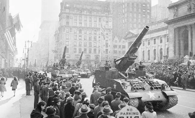 FILE - Soldiers stand at attention in their vehicles which carry 8-inch Howitzers, during the Victory Parade of the 82nd Airborne Division on Fifth Avenue in New York, Jan. 12, 1946. The parade is passing the reviewing stand in front of the Public Library, right. (AP Photo/Harry Harris, File)