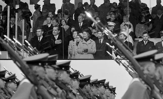 FILE - President Nixon salutes as cadets from the West Point Military Academy pass the presidential reviewing stand during the inaugural parade in Washington, D.C., Jan. 20, 1969. In the front row of the reviewing stand, from left are Doug Rogers, the President, Barbara Eisenhower, Julie Nixon Eisenhower, Pat Nixon, David Eisenhower and Mamie Eisenhower. (AP Photo, File)