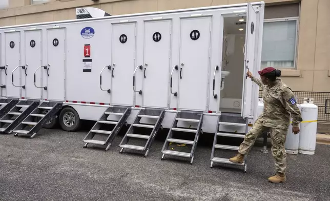 Command Sgt. Maj. Carla Stancil opens the door of the outdoor shower facilities for the up to 5,000 soldiers who will live in the GSA Regional Office Building for the Army's 250th Birthday celebration, Sunday, June 8, 2025, in Washington. (AP Photo/Kevin Wolf)