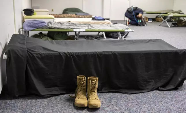 Boots sit next to a cot in one of the sleeping areas set up for the up to 5,000 soldiers who will be quartered in the GSA Regional Office Building for the Army's 250th Birthday celebration, Sunday, June 8, 2025, in Washington. (AP Photo/Kevin Wolf)