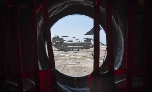 A U.S. Army CH-47 Chinook helicopter is seen through the window of another CH-47 Chinook helicopter, part of a group of aircraft that will participate in an upcoming military parade commemorating the Army's 250th anniversary and coinciding with President Donald Trump's 79th birthday, at Joint Base Andrews, Md., Thursday, June 12, 2025. (AP Photo/Mark Schiefelbein)
