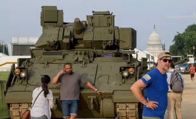 People pass by and take photos with a tank, parked on the National Mall, during preparations for an upcoming military parade commemorating the Army's 250th anniversary and coinciding with President Donald Trump's 79th birthday, Thursday, June 12, 2025, in Washington. (AP Photo/Rod Lamkey, Jr.)