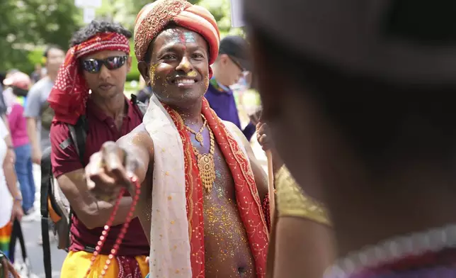 Anand Ramphal, of Silver Spring, Md., hands out beads during the World Pride parade, Saturday, June 7, 2025, in Washington. (AP Photo/Jacquelyn Martin)