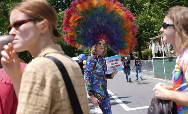 A person carrying a sign that states "these colors don't run from fascists" walks before the World Pride parade, Saturday, June 7, 2025, in Washington. (AP Photo/Julia Demaree Nikhinson)