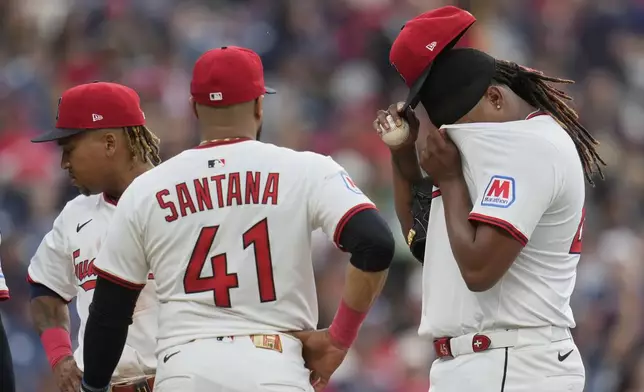 Cleveland Guardians starting pitcher Luis Ortiz, right, wipes his face with his jersey as he waits with teammates Jose Ramirez, left, and Carlos Santana (41) for Carl Willis during a mound meeting in the fifth inning of a baseball game against the Cincinnati Reds in Cleveland, Monday, June 9, 2025. (AP Photo/Sue Ogrocki)