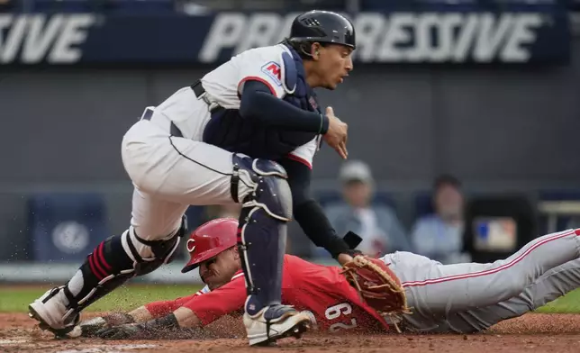Cincinnati Reds' TJ Friedl, rear, slides safely behind Cleveland Guardians catcher Bo Naylor, front, to score in the fifth inning of a baseball game in Cleveland, Monday, June 9, 2025. (AP Photo/Sue Ogrocki)