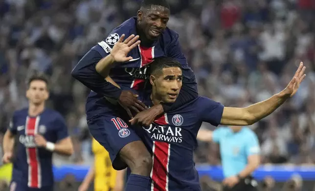PSG's Achraf Hakimi celebrates with Ousmane Dembele after scoring his side's first goal during the Champions League final soccer match between Paris Saint-Germain and Inter Milan at the Allianz Arena in Munich, Germany, Saturday, May 31, 2025. (AP Photo/Matthias Schrader)
