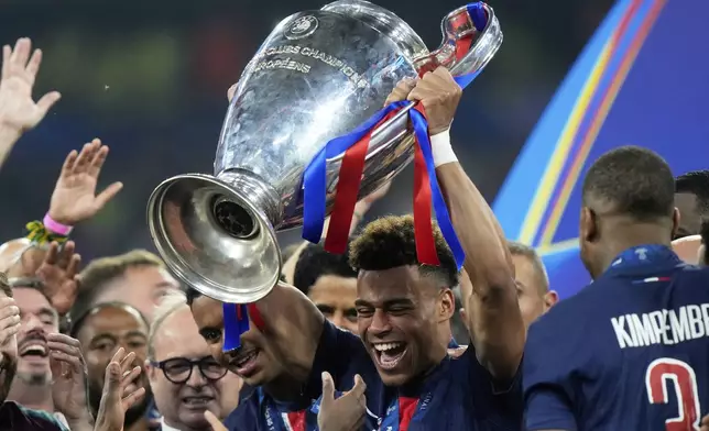 PSG's Desire Doue holds the trophy after winning the Champions League final soccer match between Paris Saint-Germain and Inter Milan at the Allianz Arena in Munich, Germany, Saturday, May 31, 2025. (AP Photo/Luca Bruno)