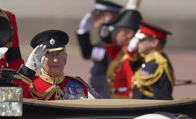 Britain's King Charles salutes as he rides in a carriage along the Mall to take part in the Trooping the Colour in London, Saturday, June 14, 2025. (AP Photo/Alberto Pezzali)