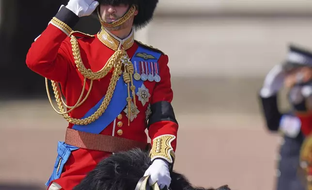 Prince William salutes as he rides along the Mall to take part in the Trooping the Colour in London, Saturday, June 14, 2025, he is wearing a black armband, as a mark of respect for the victims of the Air India plane crash. (AP Photo/Alberto Pezzali)