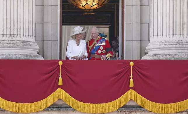 Britain's King Charles and Queen Camilla walk onto the balcony of Buckingham Palace to watch the flypast and wave at the crowds during the Trooping the Colour in London, Saturday, June 14, 2025, the king is wearing a black armband as a mark of respect to the victims of the Air India plane crash.(AP Photo/Alberto Pezzali)
