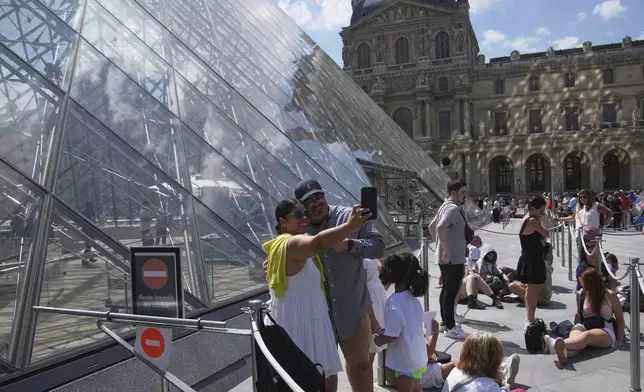 Tourists wait outside the Louvre museum which failed to open on time Monday, June 16, 2025 in Paris. (AP Photo/Christophe Ena)