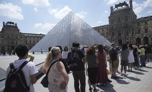 Tourists wait in line outside the Louvre museum which failed to open on time Monday, June 16, 2025 in Paris. (AP Photo/Christophe Ena)