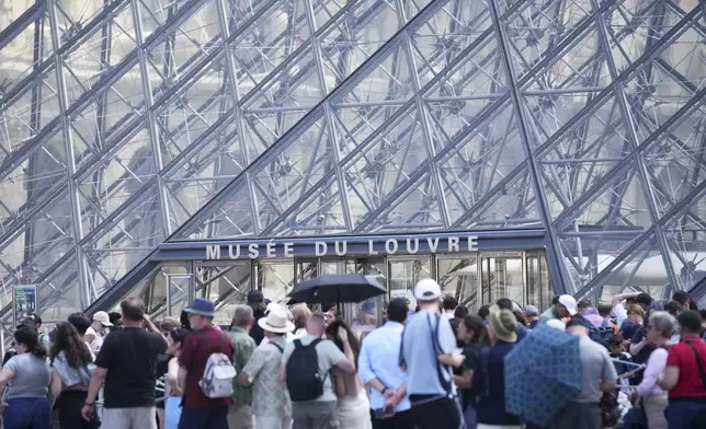 Tourists wait outside the Louvre museum which failed to open on time Monday, June 16, 2025 in Paris. (AP Photo/Christophe Ena)