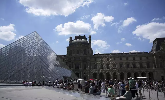 Tourists wait in line outside the Louvre museum which failed to open on time Monday, June 16, 2025 in Paris. (AP Photo/Christophe Ena)