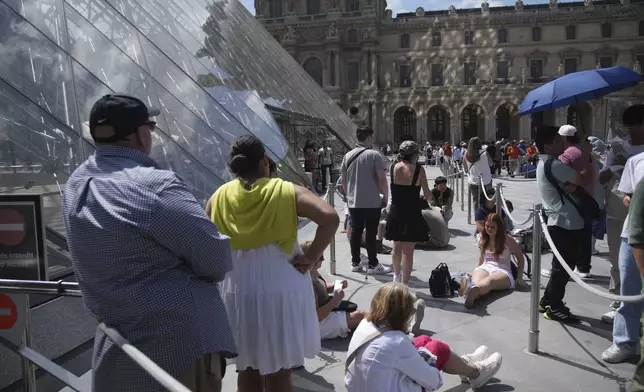 Tourists wait outside the Louvre museum which failed to open on time Monday, June 16, 2025 in Paris. (AP Photo/Christophe Ena)