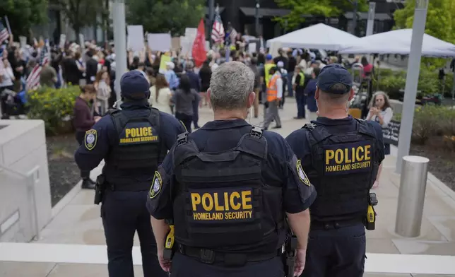Department of Homeland Security police officers stand as protesters gather outside the Federal Courthouse before arguments whether Kilmar Abrego Garcia can be released from jail on Friday, June 13, 2025 in Nashville, Tenn. (AP Photo/George Walker IV)