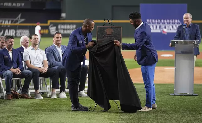 Former Texas Rangers players Adrian Beltre, left, and Elvis Andrus unveil a plaque honoring Andrus during a ceremony where he was inducted into the clubs hall of fame before a baseball game against the Seattle Mariners Saturday, June 28, 2025, in Arlington, Texas. (AP Photo/Tony Gutierrez)